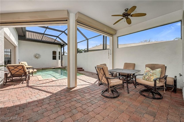 view of patio / terrace featuring a ceiling fan and glass enclosure