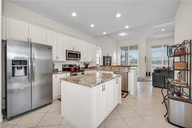 kitchen featuring light tile patterned floors, a kitchen island, appliances with stainless steel finishes, a peninsula, and white cabinetry