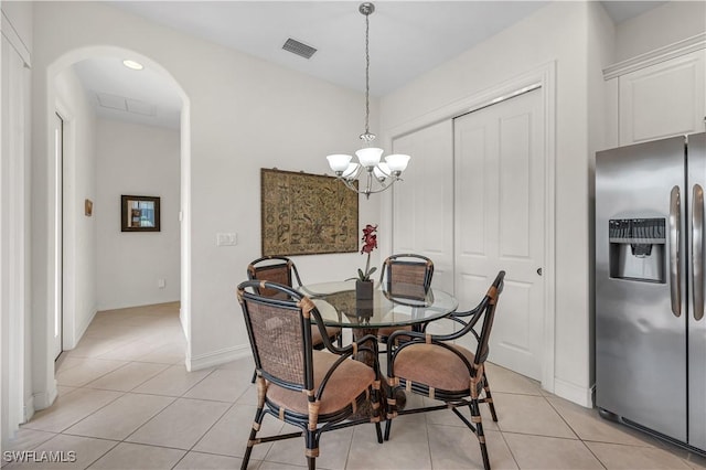 dining space with light tile patterned floors, arched walkways, a chandelier, and visible vents