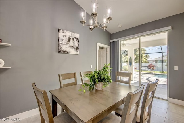 dining area featuring an inviting chandelier, baseboards, vaulted ceiling, and light tile patterned flooring