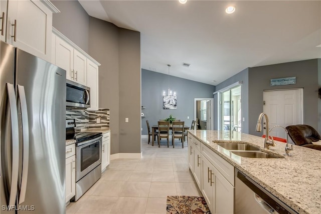 kitchen featuring light stone counters, light tile patterned flooring, stainless steel appliances, a sink, and white cabinetry