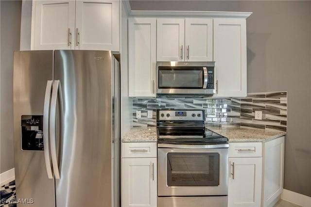 kitchen with light stone counters, stainless steel appliances, white cabinetry, baseboards, and backsplash