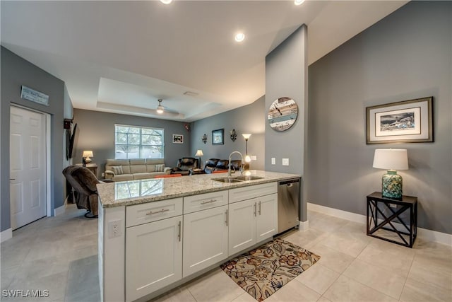 kitchen featuring a raised ceiling, dishwasher, open floor plan, white cabinetry, and a sink