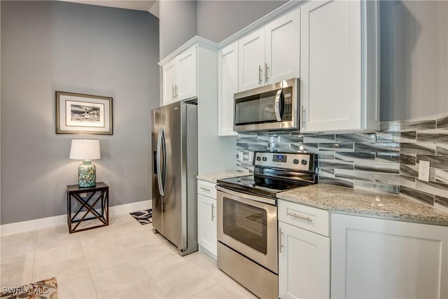 kitchen featuring white cabinets, baseboards, appliances with stainless steel finishes, light stone countertops, and tasteful backsplash