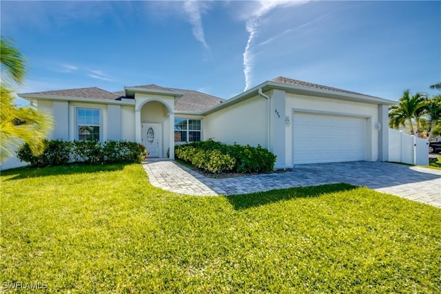 view of front of house featuring stucco siding, an attached garage, fence, decorative driveway, and a front yard