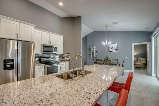 kitchen with light stone counters, stainless steel appliances, visible vents, white cabinets, and a sink