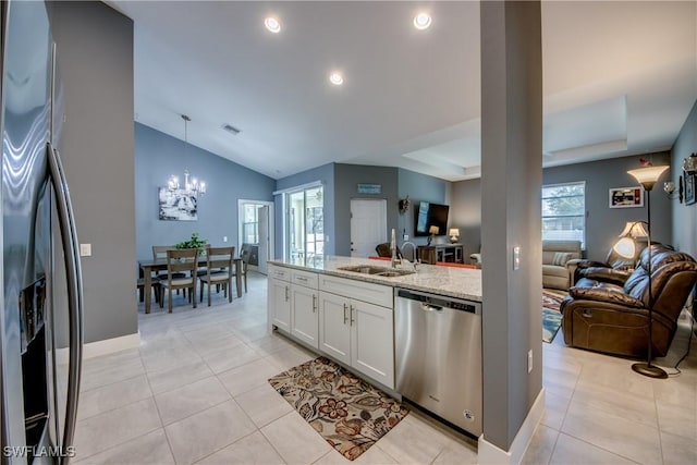 kitchen with stainless steel appliances, a sink, a healthy amount of sunlight, open floor plan, and light stone countertops