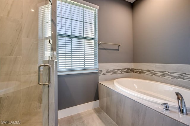 bathroom featuring tile patterned flooring, a shower stall, a bath, and baseboards