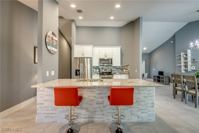 kitchen featuring white cabinetry, appliances with stainless steel finishes, light stone counters, and a sink