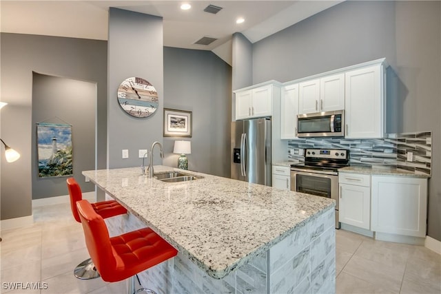 kitchen featuring appliances with stainless steel finishes, visible vents, a sink, and decorative backsplash