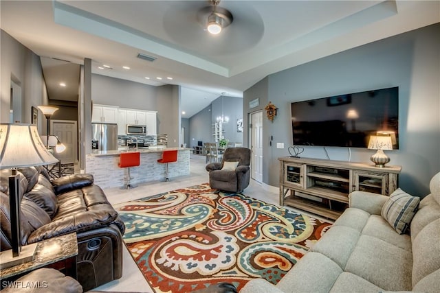 living room featuring recessed lighting, a raised ceiling, visible vents, and ceiling fan with notable chandelier