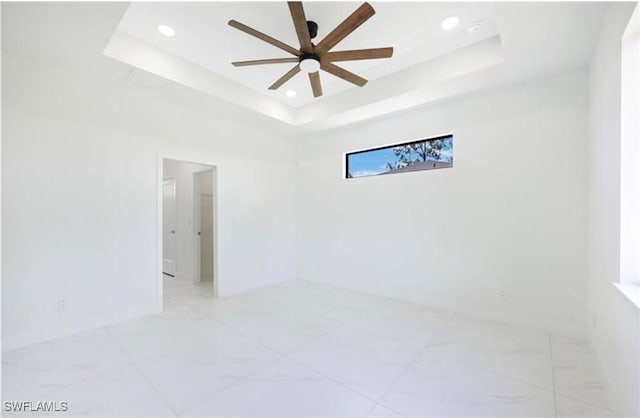 spare room with ceiling fan and a tray ceiling