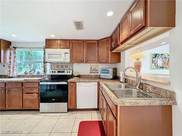 kitchen featuring white appliances, a toaster, visible vents, brown cabinetry, and a sink