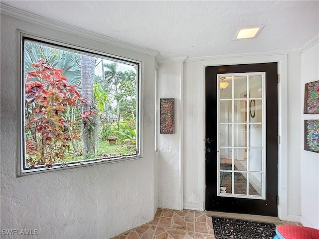 doorway with a textured wall, ornamental molding, and a wealth of natural light