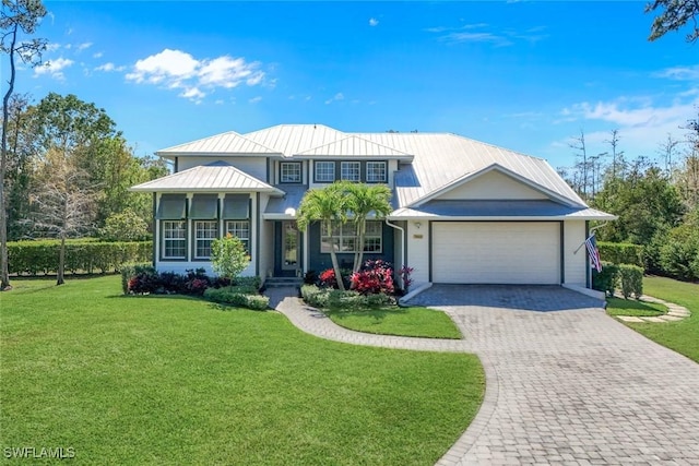 view of front of property with a front lawn, decorative driveway, metal roof, and an attached garage