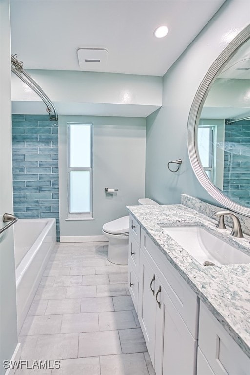 full bathroom with vanity, tiled shower / bath, and toilet