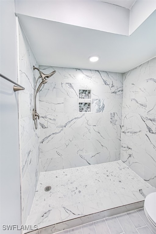 bathroom with toilet and a tile shower