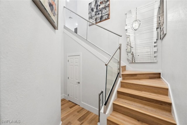 stairs with hardwood / wood-style floors and a towering ceiling