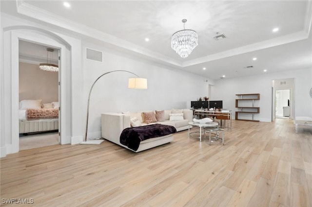 living room featuring light hardwood / wood-style flooring, crown molding, a raised ceiling, and an inviting chandelier