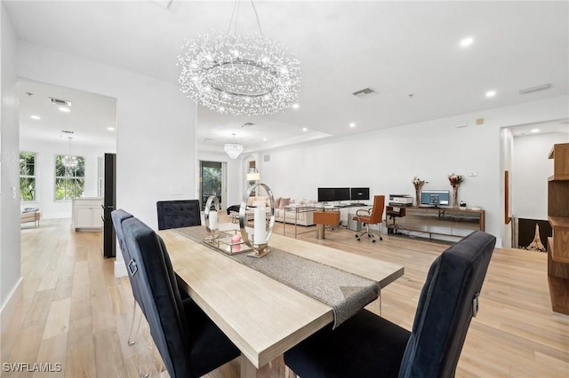 dining room with light hardwood / wood-style floors and a notable chandelier