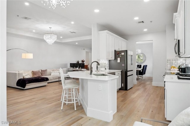 kitchen featuring white cabinetry, light hardwood / wood-style floors, sink, tasteful backsplash, and appliances with stainless steel finishes