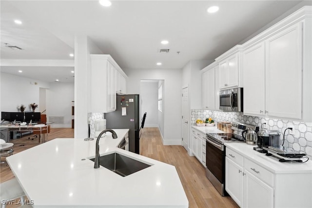 kitchen with appliances with stainless steel finishes, white cabinetry, tasteful backsplash, and sink