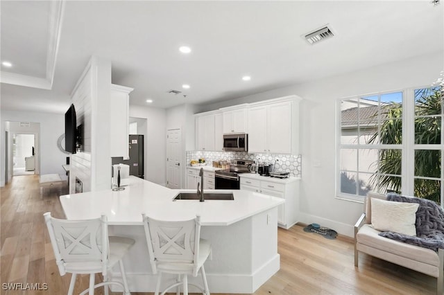 kitchen featuring stainless steel appliances, light hardwood / wood-style floors, sink, backsplash, and white cabinets