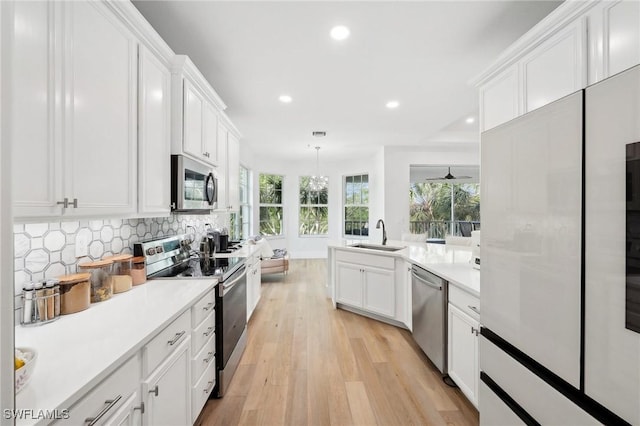 kitchen with tasteful backsplash, hanging light fixtures, stainless steel appliances, white cabinets, and sink