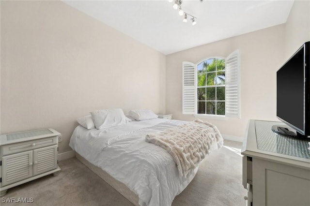 bedroom featuring light carpet and rail lighting