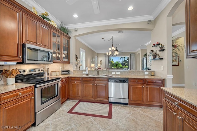 kitchen featuring stainless steel appliances, glass insert cabinets, a sink, and crown molding