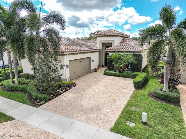 mediterranean / spanish-style house with decorative driveway, an attached garage, a tile roof, and stucco siding