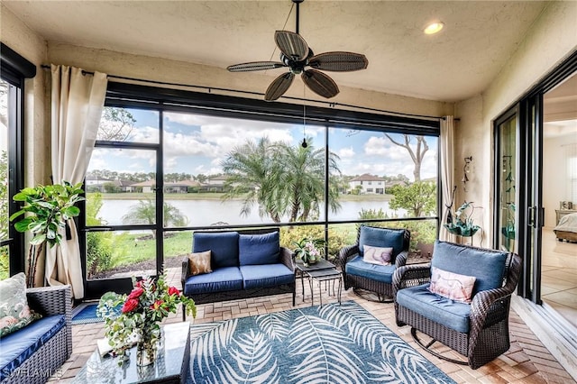 sunroom / solarium featuring a water view and ceiling fan