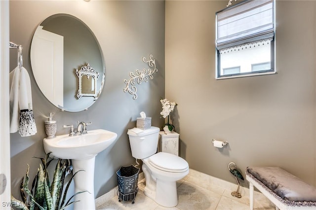 bathroom featuring baseboards, a sink, toilet, and tile patterned floors