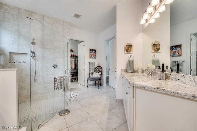 bathroom featuring a walk in closet, visible vents, a shower stall, and vanity