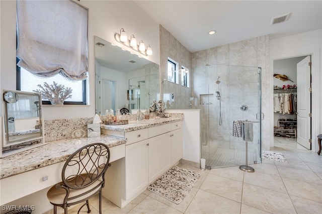 bathroom with visible vents, a spacious closet, a shower stall, vanity, and tile patterned flooring