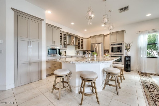 kitchen featuring light tile patterned floors, a center island with sink, visible vents, wall chimney exhaust hood, and stainless steel appliances