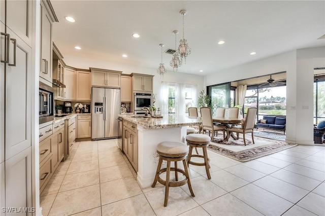 kitchen featuring light tile patterned floors, stainless steel appliances, recessed lighting, a sink, and a kitchen bar