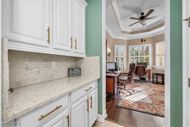 home office with ceiling fan, crown molding, a raised ceiling, and wood-type flooring