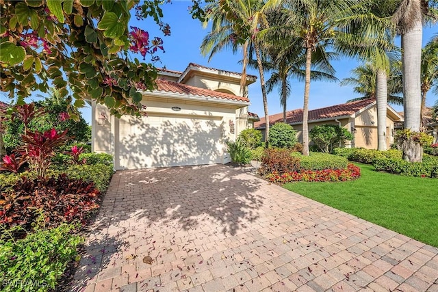 mediterranean / spanish-style home with a garage and a front lawn