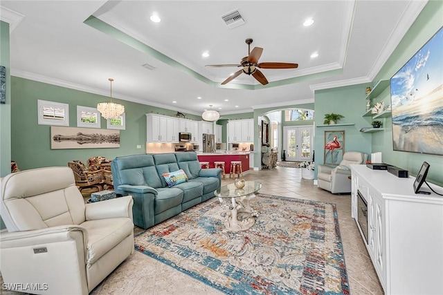 living room featuring french doors, ceiling fan with notable chandelier, crown molding, and a raised ceiling