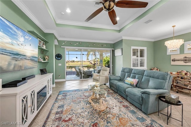 living room featuring ceiling fan with notable chandelier, light tile patterned floors, crown molding, and a raised ceiling