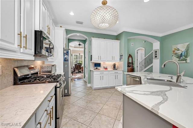 kitchen featuring appliances with stainless steel finishes, light stone countertops, crown molding, sink, and white cabinetry