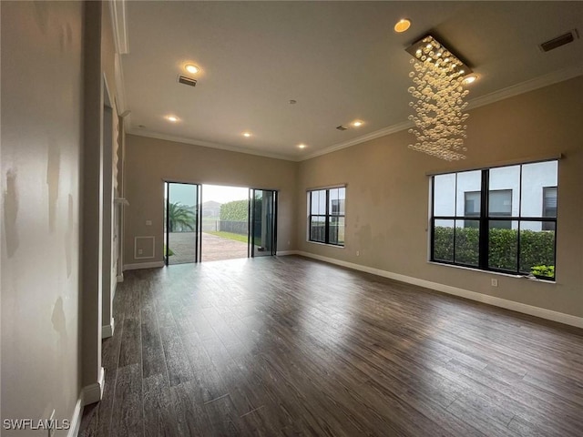 empty room featuring dark wood-style flooring, visible vents, crown molding, and baseboards