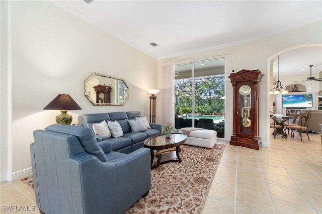 living area with light tile patterned floors, visible vents, baseboards, a ceiling fan, and crown molding