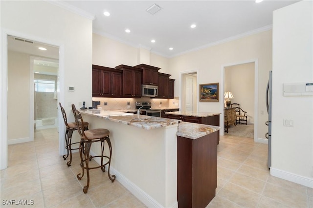 kitchen with visible vents, a kitchen island, appliances with stainless steel finishes, ornamental molding, and a peninsula