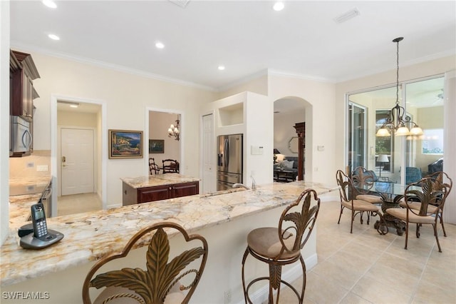 kitchen featuring appliances with stainless steel finishes, a center island, a chandelier, and light stone countertops