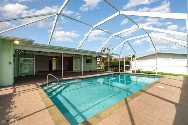 view of swimming pool with glass enclosure, fence, a fenced in pool, and a patio