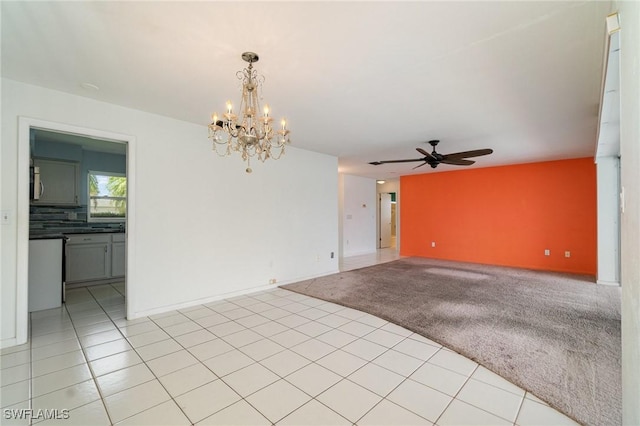 empty room with light carpet, light tile patterned floors, baseboards, and ceiling fan with notable chandelier