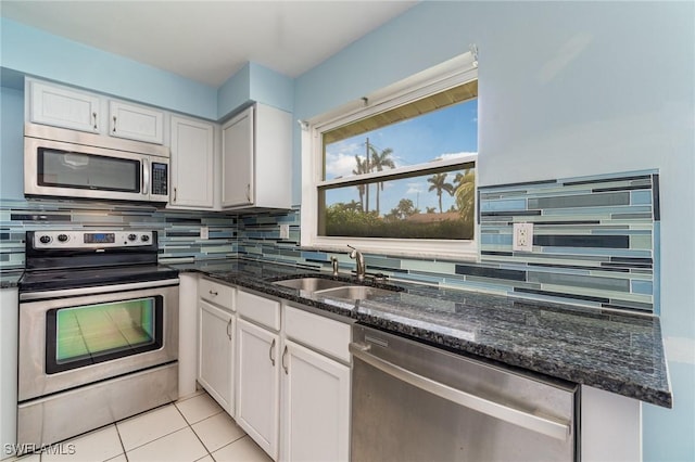 kitchen with light tile patterned floors, tasteful backsplash, stainless steel appliances, white cabinetry, and a sink