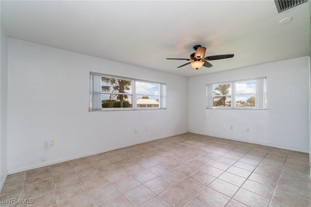 empty room with light tile patterned floors, ceiling fan, visible vents, and baseboards